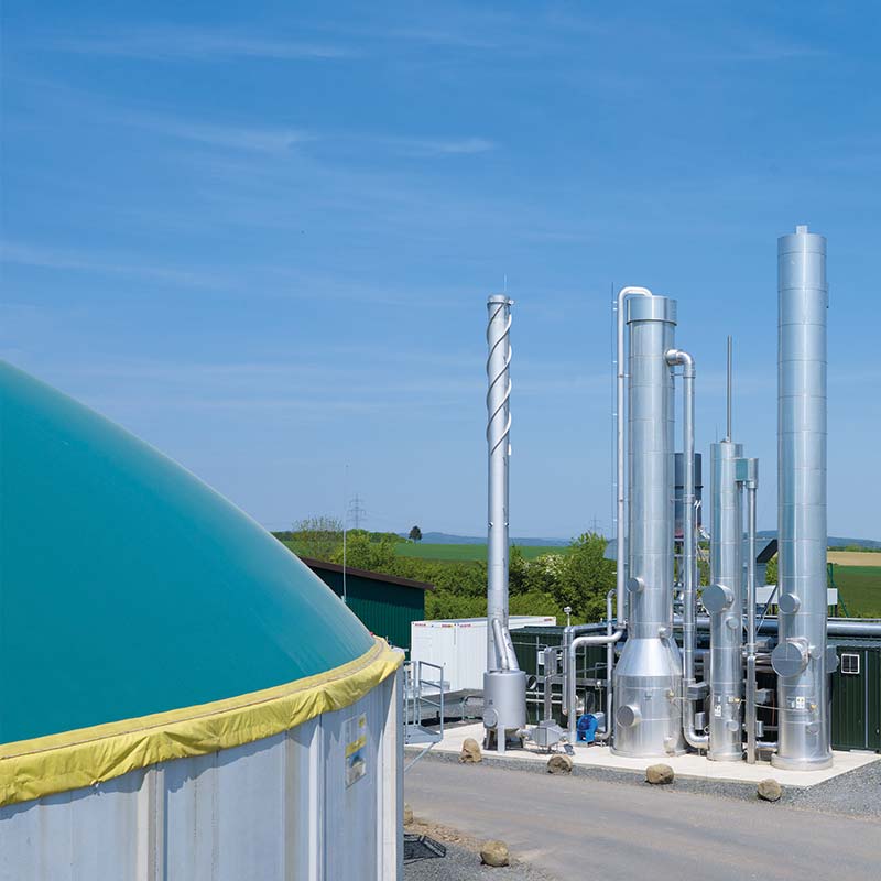 Produkte und Dienstleistungen für Biogas Anlagenbetreiber. Hier zu sehen eine Biomethananlage. Im Vordergrund der Fermenter und im Hintergrund die Gasaufbereitung